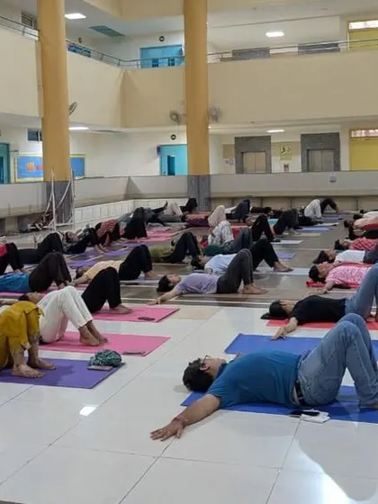 Participants practicing a reclining asana during a session at a college. We ensure our sessions are suitable for all fitness levels, making Yoga accessible to everyone.