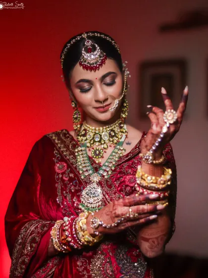 A candid portrait of the bride in her rich red velvet lehenga. Her eyes are closed as she admires her hands, a quiet moment of reflection filled with anticipation for the ceremony ahead.