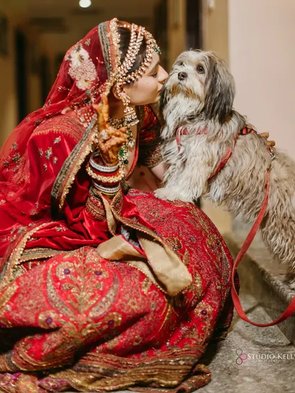 A heartwarming moment as the bride shares a kiss with her furry friend, a special member of the family.