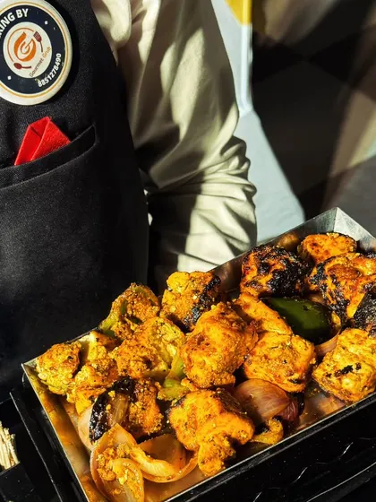 A server presenting a tray of succulent paneer tikka, fresh from the tandoor and ready to be served to guests.