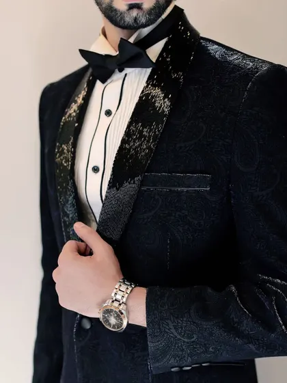 A detailed shot of the black paisley tuxedo, focusing on the contrast between the patterned fabric and the shimmering lapel. It’s a masterclass in texture and tone for formal occasions.