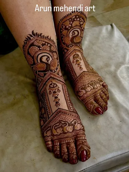 Elegant foot mehendi featuring the graceful Indian peacock. The intricate feathers and patterns cover the feet beautifully.