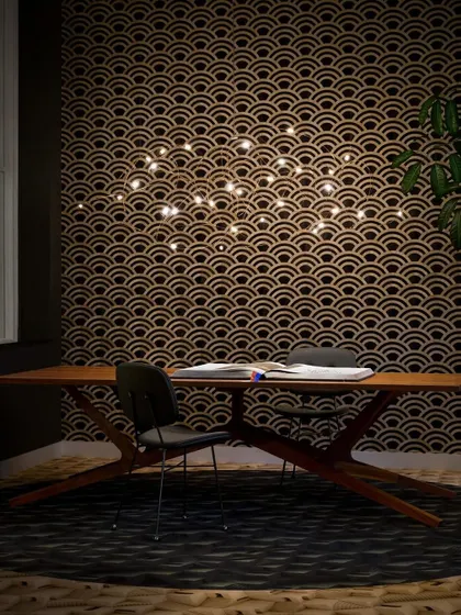 The horizontal version of the Flock of Light, suspended over a desk. The delicate bronze wires trace a path through the air, connecting the small, bright LEDs.