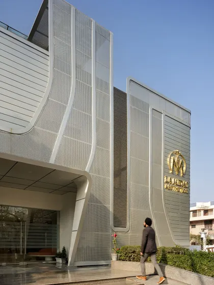 The fluid facade of La Midas Wellness Centre, an adaptive reuse of a 20-year-old residence, is inspired by the female form. The double-skin screen acts as sculptural "street furniture," creating a distinct identity within its residential context.