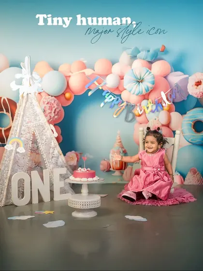 A tiny human and a major style icon. This little girl celebrates turning one in a vibrant pink dress, surrounded by a colorful donut and candy-themed backdrop that is as sweet as she is.