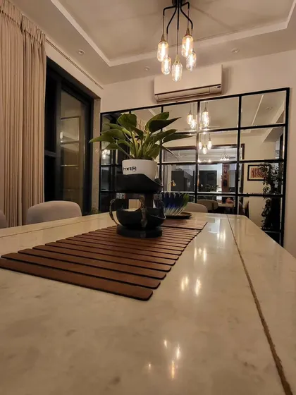 A full mirror wall with a modern black grid pattern visually doubles the size of this dining area, adding depth and reflecting light throughout the space.
