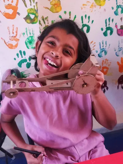 The pure joy of creation! This student is thrilled with the wooden car she assembled and is ready to play.