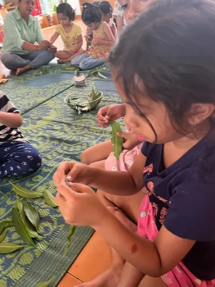 A child carefully inspects a leaf before using it in a craft. This activity encourages close observation of nature's details and textures.