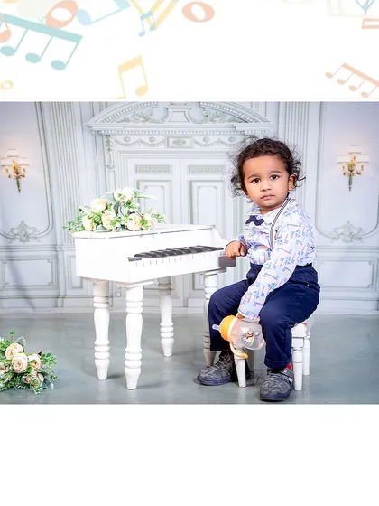 A little musician with a thoughtful expression. This portrait captures a quiet moment at the piano, showcasing the elegant and classic theme.