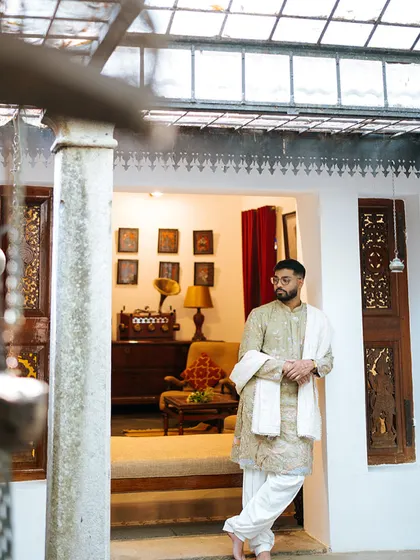 The groom looking dapper in his traditional attire, posing in a heritage room before the ceremony.