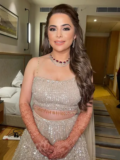 The half-up hairstyle keeps the hair neatly away from the face, showing off the bride's beautiful makeup and jewelry.