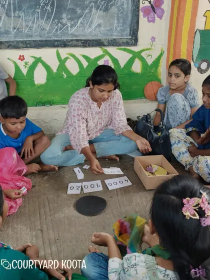 A volunteer uses number cards to teach math in a fun, interactive way at the Makkala Masti summer camp.