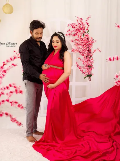 A lovely couple's portrait in our pink floral setup. The husband's hand on the baby bump is a classic gesture of love and connection.
