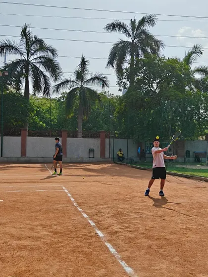 Two players engaged in a practice match on the clay court. Regular match play is essential for developing strategy and mental toughness.