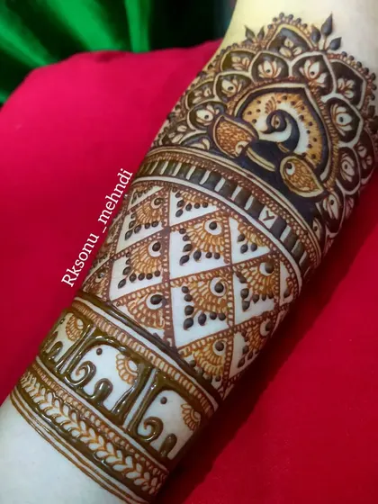A close-up of the forearm detail from a bridal set. This image highlights the intricate work in the peacock mandala and the bands of elephant and geometric patterns.