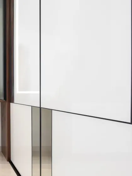 This image shows a close-up of a white high-gloss Aristo sliding wardrobe next to an integrated vanity. This is a great example of how I combine different functional elements into one seamless unit.