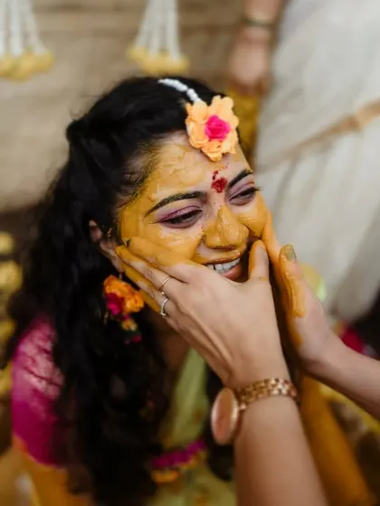 A close-up of a bride's joyful expression as her loved ones apply Haldi. We focus on capturing the emotions and connections that make these rituals so special.