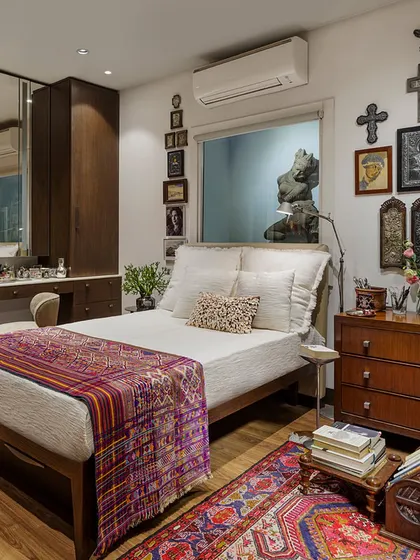 The bedroom in the Courtyard Home is a deeply personal space, featuring a collection of Christian icons and crucifixes from the owner's travels. A hand-woven Bhutanese textile and an antique Kurdish kilim add layers of texture and story.