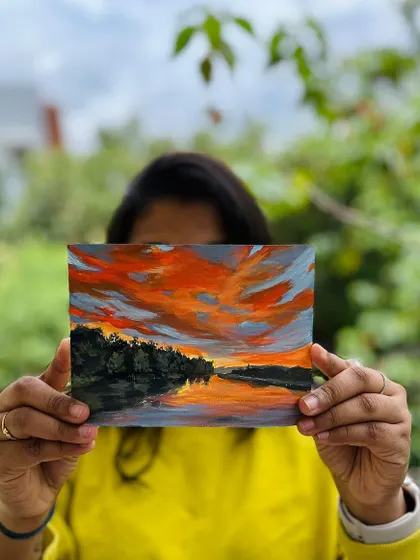 Holding up the "Sundown Magic" painting to the camera.