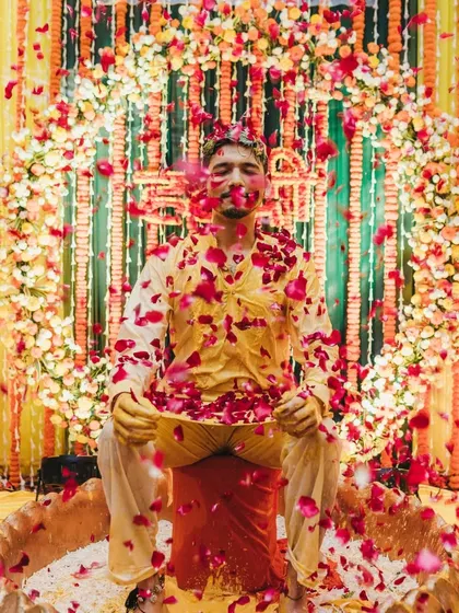 A beautiful final shot of the groom being showered with red rose petals after the haldi and milk rituals are complete.