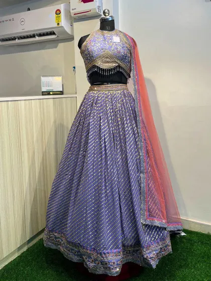 A front view of the purple lehenga, showing the embellished halter blouse and the flowy skirt. It's paired with a contrasting pink dupatta.