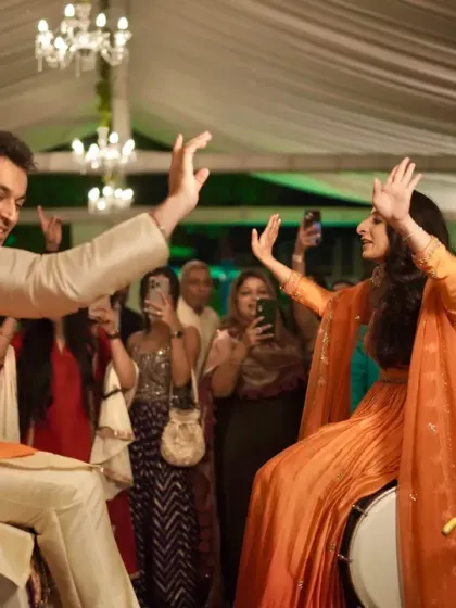 The couple having fun and dancing on top of dhols, a high-energy moment from their pre-wedding celebrations.