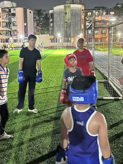 Our coach talking strategy with the youth team during an outdoor training session. We prepare them not just to fight, but to think like a boxer.