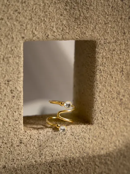 A detailed macro shot of a gold spiral ring. The tight framing and textured background highlight the unique design and craftsmanship of the piece, perfect for a product page.
