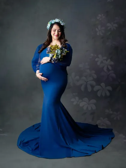 A floral crown and matching bouquet add a soft, romantic touch to this portrait in a royal blue gown, creating a beautiful and cohesive look.