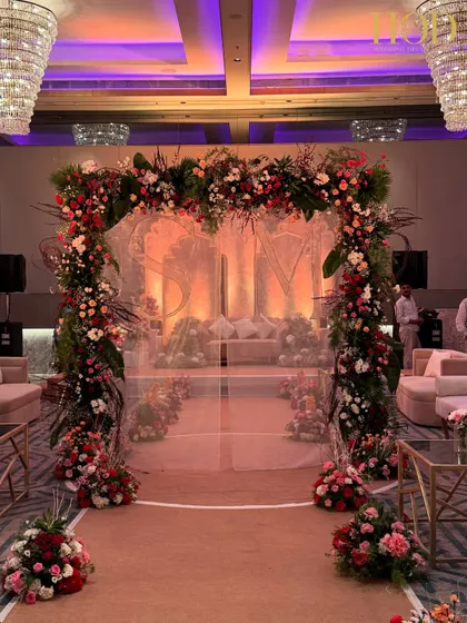A full shot of the floral arch entrance, showing how it frames the stage in the distance. This creates a beautiful sense of depth and makes for a stunning photo opportunity for the couple and their guests.