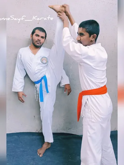 Karatekas in action. One student practices a high kick with assistance, a great way to improve flexibility and kicking technique.