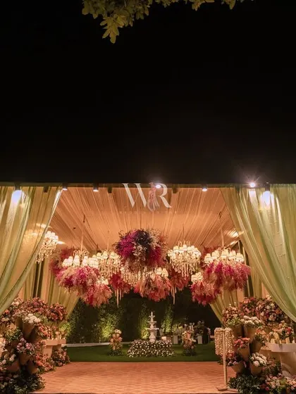 The entrance to a floral fantasy. We used soft green drapes to frame a pathway leading to a space filled with chandeliers adorned with colorful dried flowers, setting a whimsical and enchanting tone from the very beginning.