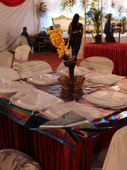 A simple yet elegant table setup with a holographic tablecloth and floral centerpiece, ready for guests to be seated.