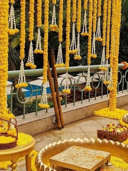 A poolside Haldi setup with traditional marigold decor. The contrast of the bright yellow flowers against the blue water is always a stunning combination.