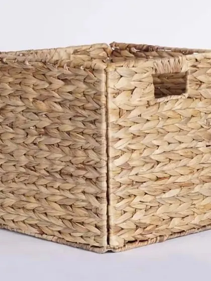 A foldable, square storage cube woven from water hyacinth, featuring convenient cutout handles. This practical design is perfect for cube shelving units, offering a stylish and eco-friendly way to conceal clutter.