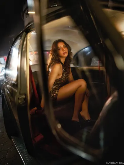 Looking into the car from the outside, this shot creates a voyeuristic and cinematic feel. The composition frames the model perfectly within the classic car's silhouette.
