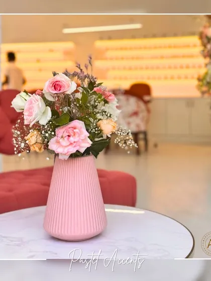Pastel accents, like this pink vase with fresh roses, are used to add soft pops of color throughout the studio. These small decorative elements contribute to the playful and creative atmosphere, contrasting beautifully with the clean, modern design of the space.
