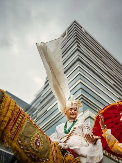The Baraat is a beautiful storm of energy and emotion. I love finding unique angles, like this low perspective, to show the groom's grand entrance against a modern city skyline, a blend of tradition and today.