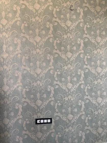 A vintage-style damask wallpaper in a subtle sage green, adding a classic touch to the room.