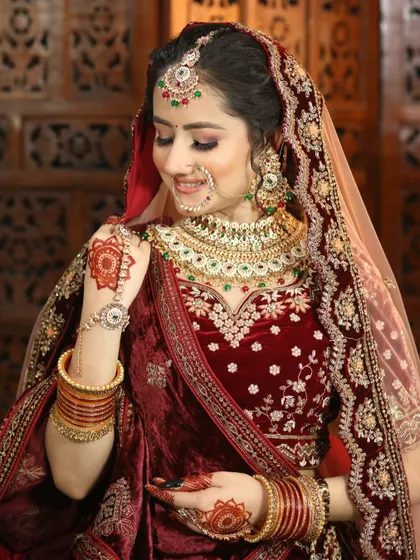 This bride's shy smile is captured perfectly. Her makeup is soft and pretty, with a focus on rosy cheeks and gently defined eyes to match her velvet maroon lehenga.