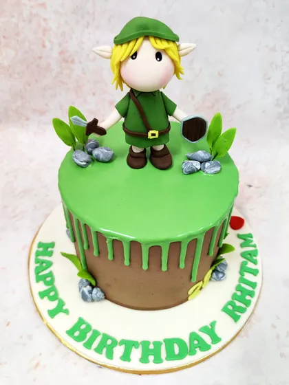 We venture into the land of Hyrule with this Legend of Zelda inspired cake. A detailed fondant figure of the hero, Link, stands ready for adventure on a field of green drip icing, making this the perfect quest for any video game enthusiast's birthday.