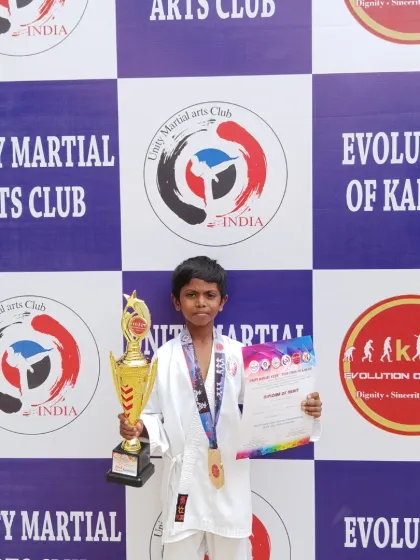 A young student holds his trophy and medal, a reward for his hard work and discipline in preparing for the championship.