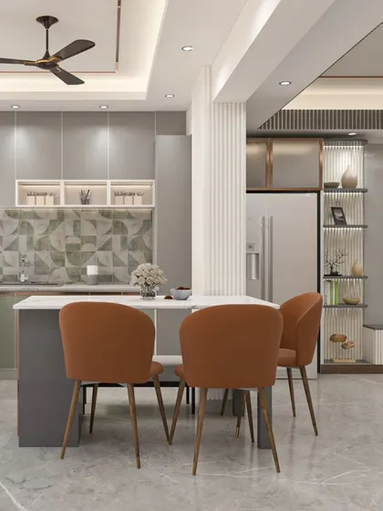 An open-plan kitchen and dining area from our Bhagalpur project. The design features sage green and grey cabinets, a patterned tile backsplash, and a functional island that doubles as a dining table.