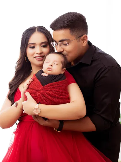 A tender moment between new parents and their baby. The focus is on their loving expressions and the peaceful sleep of their newborn.