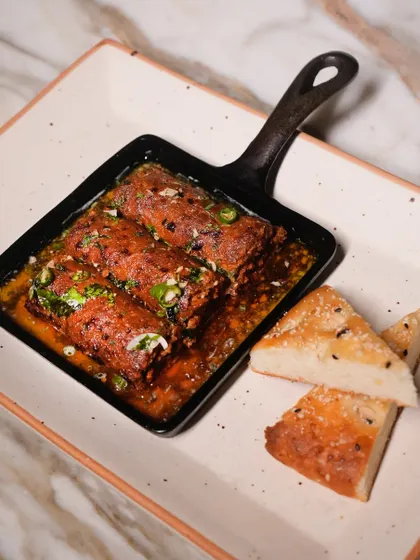 My smoky and spicy Mutton Seekh Kebabs arrive sizzling in their own juices, served in a cast-iron pan with soft, house-made bread for mopping it all up.
