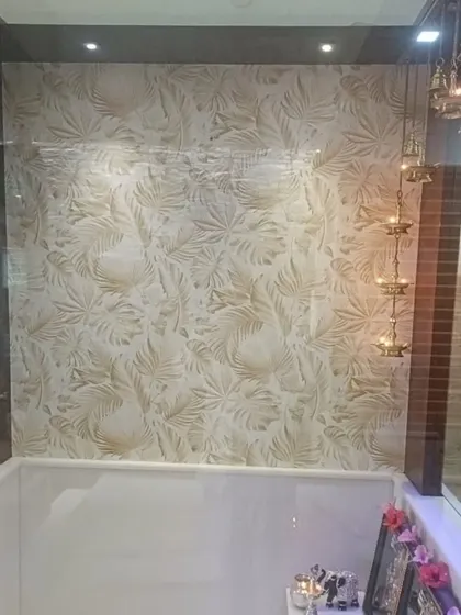 A subtle leaf-patterned wallpaper installed in a pooja room or prayer area. The light, neutral design adds a sense of peace and serenity to the sacred space.