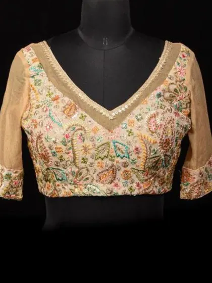 A mannequin showcasing our cream georgette blouse with intricate, multi-colored embroidery and sheer sleeves.
