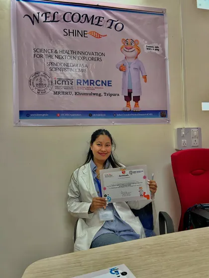 Holding a certificate of participation for the 'SHINE' event, where I helped mentor students in the field of medical research.