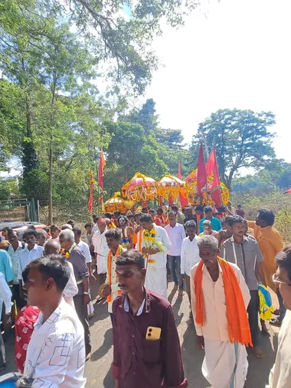 The procession of deities, led by an entourage of dancers and drummers, moving through the forest path.
