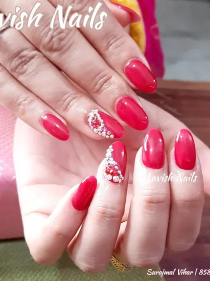 Classic bridal red nails are elevated with accent nails featuring a beautiful crescent of pearls and crystals for a touch of glamour.